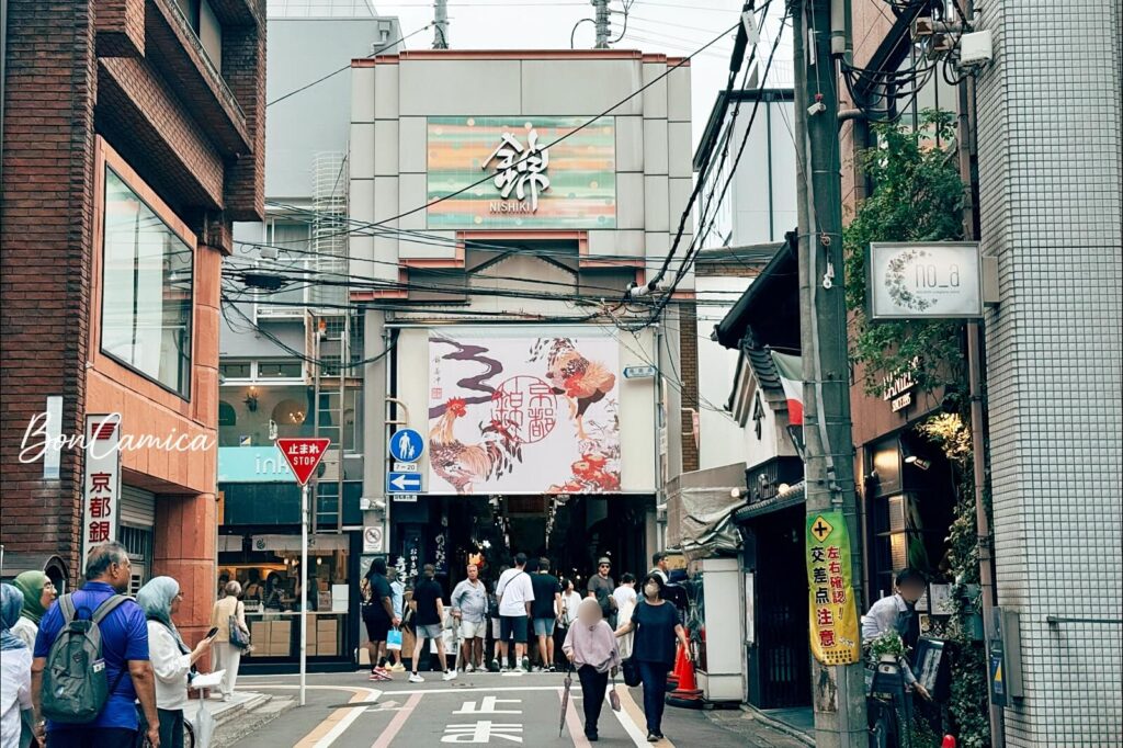京都錦市場入口,狹窄街道上有行人與電線交錯的城市景觀