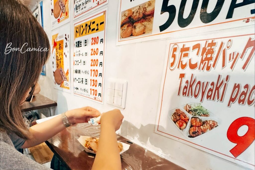 博士章魚燒店內的菜單牆與食客將美乃滋擠在小丸子上