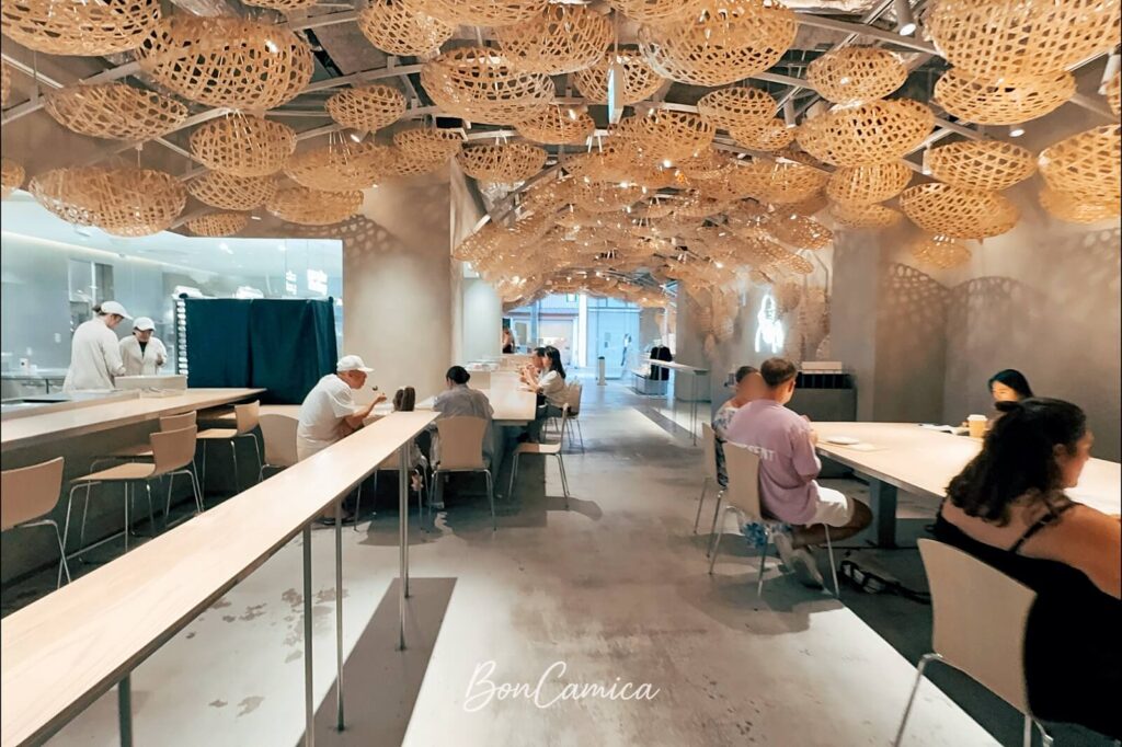 Koe Donuts 甜甜圈店,水泥工業風搭配竹簍造型天花板的室內設計,客人們在用餐區品嚐甜甜圈與飲品
