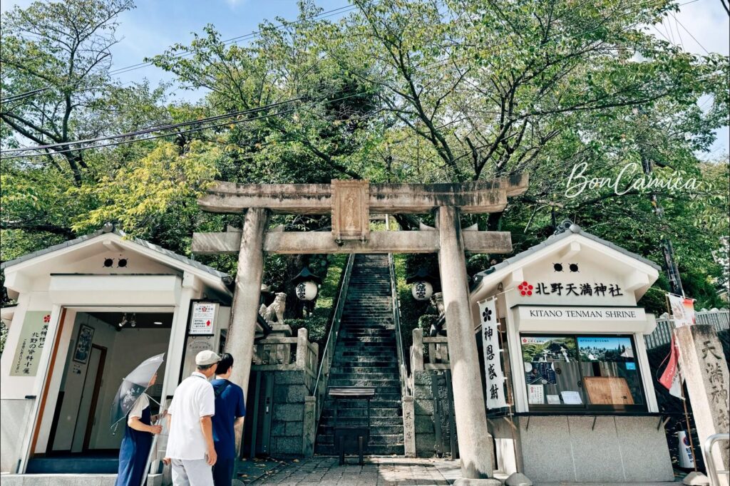 北野天滿神社的石造鳥居入口、售票處與後方筆直高聳的石階。