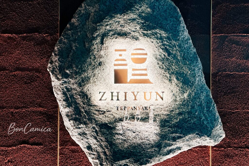 旨醞鐵板餐廳的牆上石板LOGO，打光照出中文字體「醞」與英文字體"ZHIYUN"